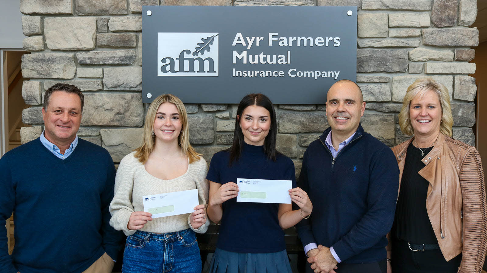two students standing with AFM Agent Miguel, and AFM CEO Jeff Whiting, and AFM COO Jodi Meiring, at Ayr Farmers Mutual Insurance Company